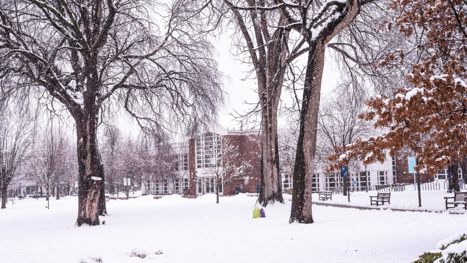 Snow covers Macalester's Great Lawn. The Campus Center is visible in the distance.