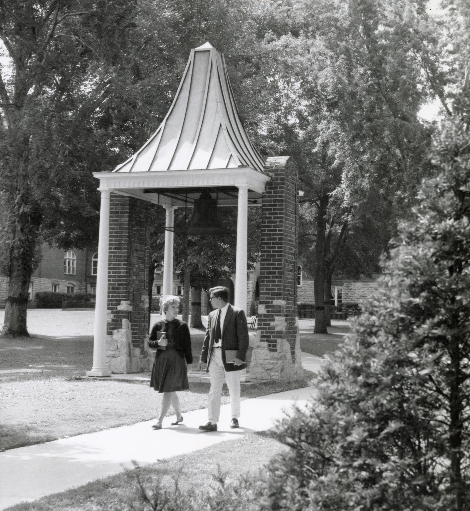 Two people walk past the Bell Tower.