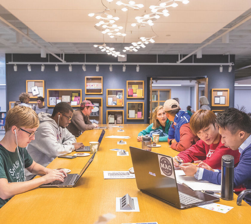 Students on their laptops at a long table in the Idea Lab.