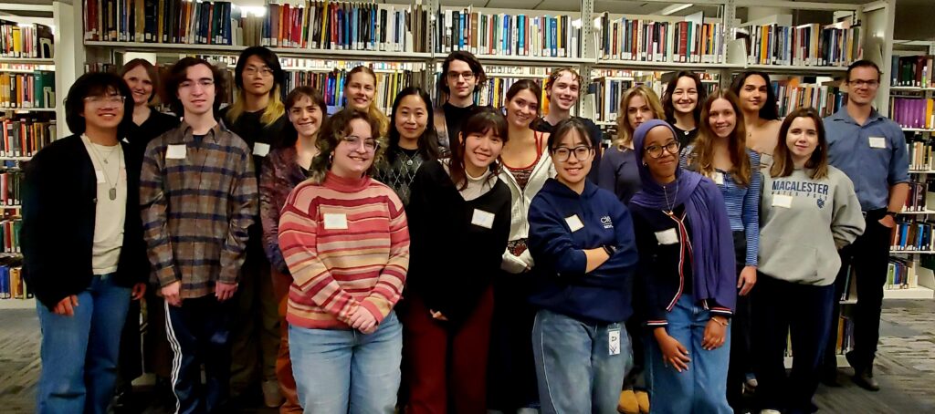 Photo of Writing Center tutors and staff standing in front of library stacks.