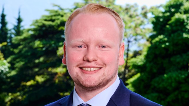 Robert Pennington smiling at camera while wearing a blue-navy suit.