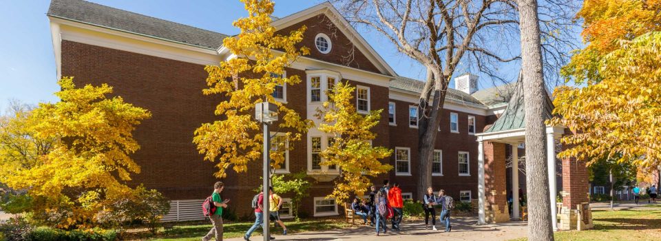 Students walking in front of Weyerhaeuser Hall in autumn.