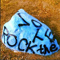 Photo of the Macalester Rock, painted bright blue and reading "ROCK THE VOTE."