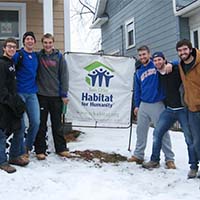Photo of students posing with a Habitat for Humanity sign