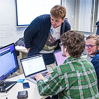 Photo of three students working together over a computer