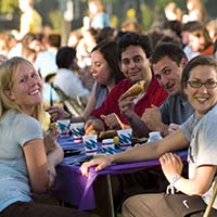 Photo of students smiling for the camera over a picnic