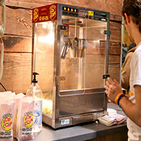 Photo of a student standing in front of a popcorn machine