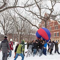 Photo of students pushing a ball outdoors in snow