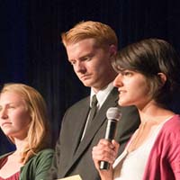 Photo of three students; one is holding a microphone