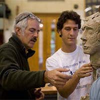 Photo of a student and a professor talking about the student's sculpture