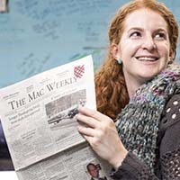 Photo of a student holding a copy of the Mac Weekly