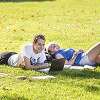 Photo of two students laying on the Macalester lawn