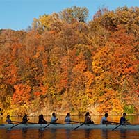 Photo of students rowing down a river on an autumn day