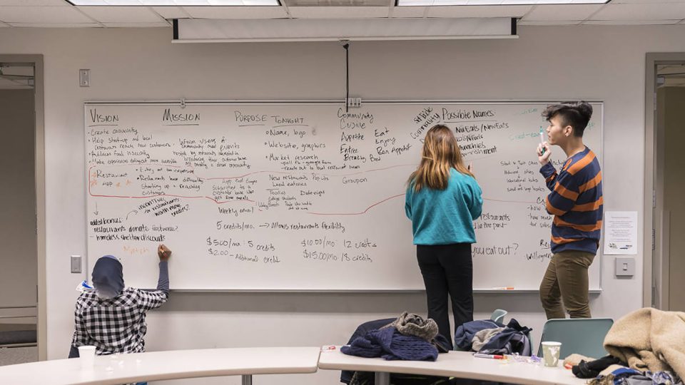 Photo of three students working at a whiteboard