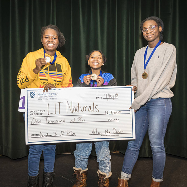 Photo of three students holding a giant check