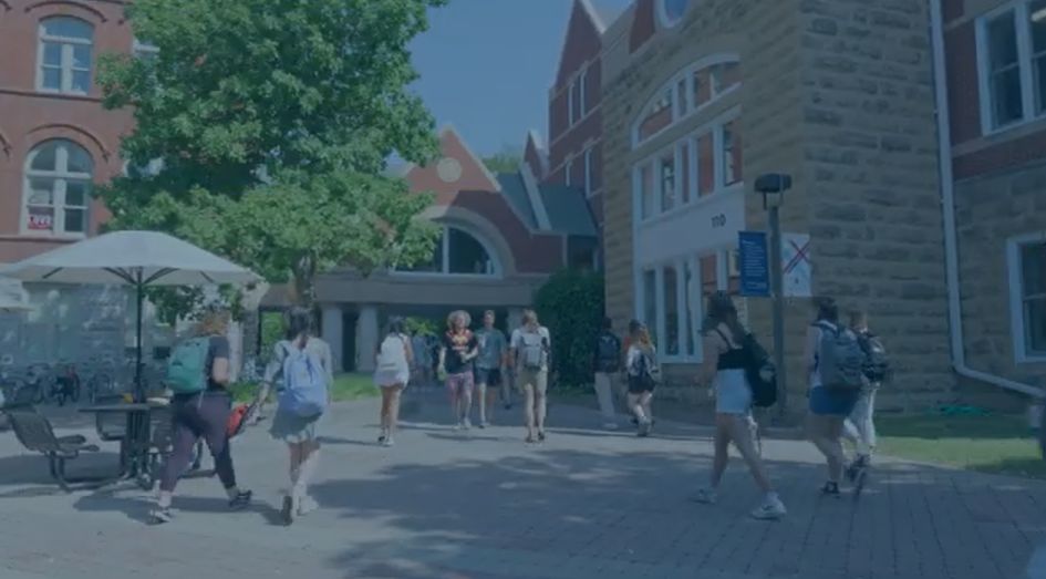 Students walk across Macalester campus on a bright sunny day.