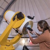 Photo of a student in front of the Macalester observatory
