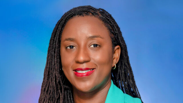 Demoya Gordon ’06 poses in front of a blue background