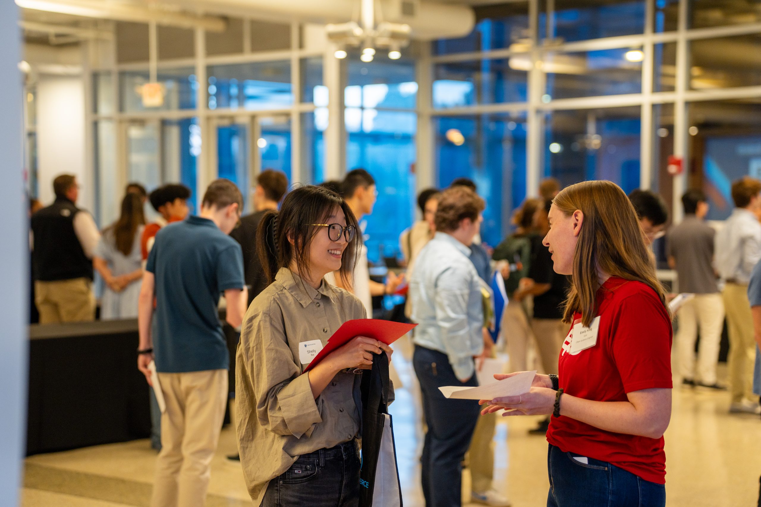 An employer talks to a student. In the background, students talk to other employer represenatives in Kagin Ballroom.