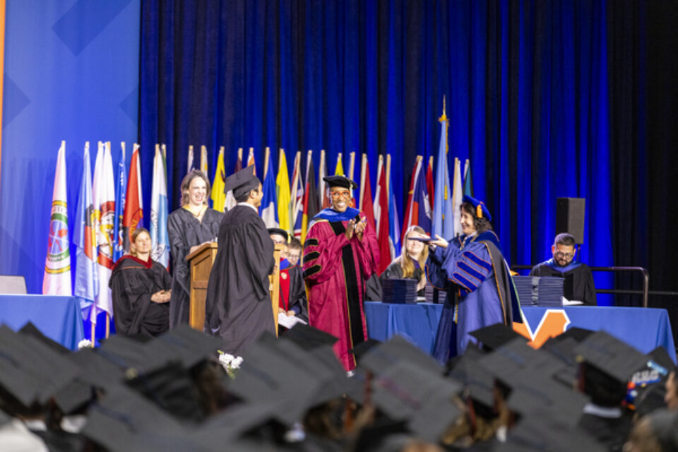 A 2025 graduate crosses the stage to accept their diploma from President Rivera.