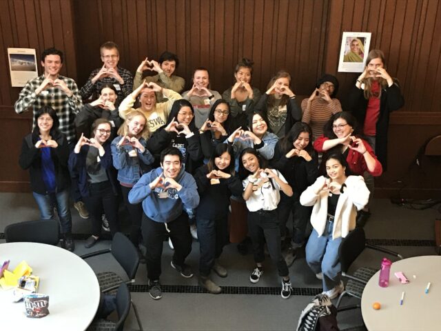 Students pose for a picture while holding their hands up in heart shapes
