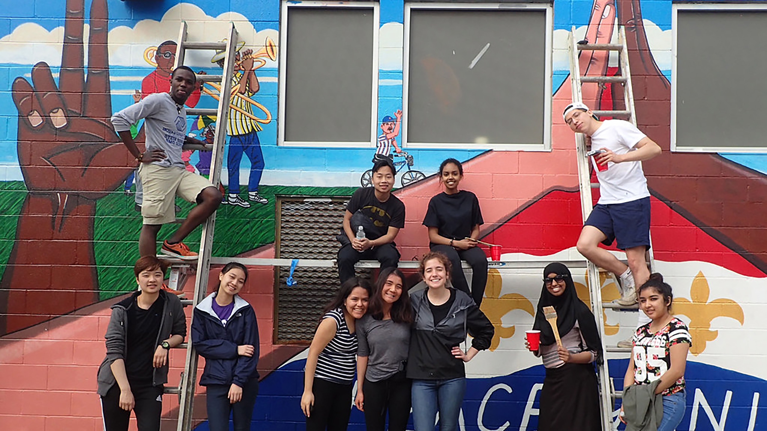 Eleven students posing with a mural they painted