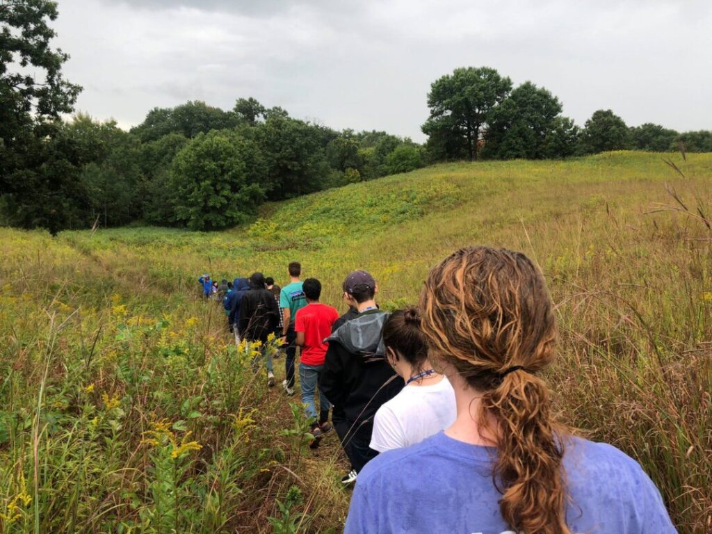 Students walking in a line through a field