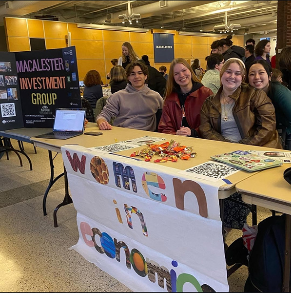 Leaders of Women in Economics and Macalester Investment Group sit behind table at organization fair