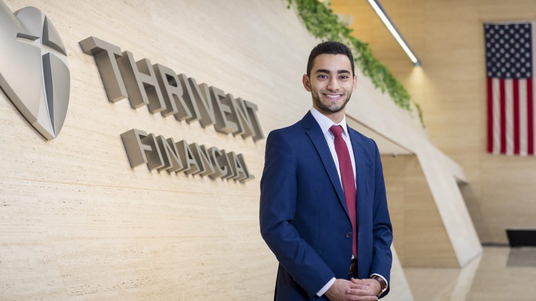 Student wearing a suit standing in the lobby of Thrivent Financial, their internship site