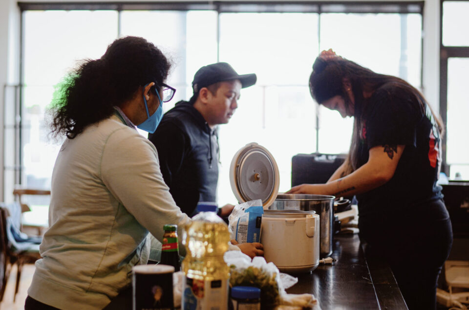 Nethmi Bathige ’22 (foreground) cooks meals with staff at Urban Roots as part of her Action Fund project during the Spring of 2022.