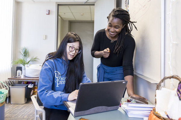 Professor and student look at laptop together