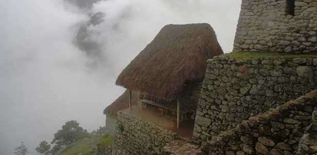A house near a cliff surrounded by clouds