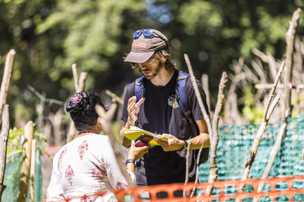 Student talks to a farmer while holding a clipboard