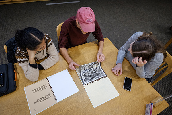 Students sit around a table examining historical documents