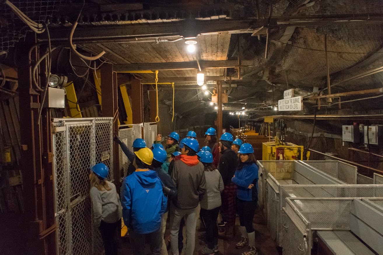 A bunch of kids in hard hats explore a mine