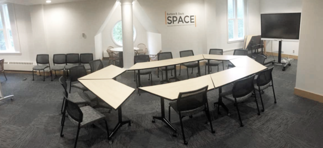 Barbara B Davis Space in library. Has a round conference table and chairs, and a large TV