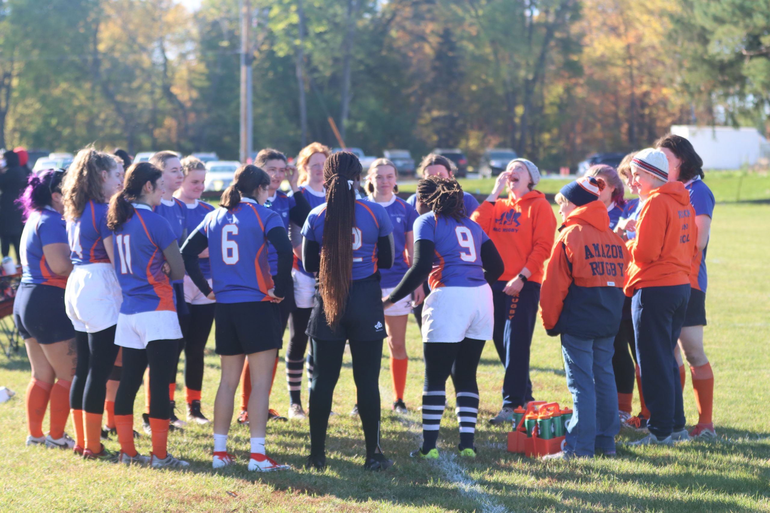 The Mac women's rugby team gathers in a circle at a game.