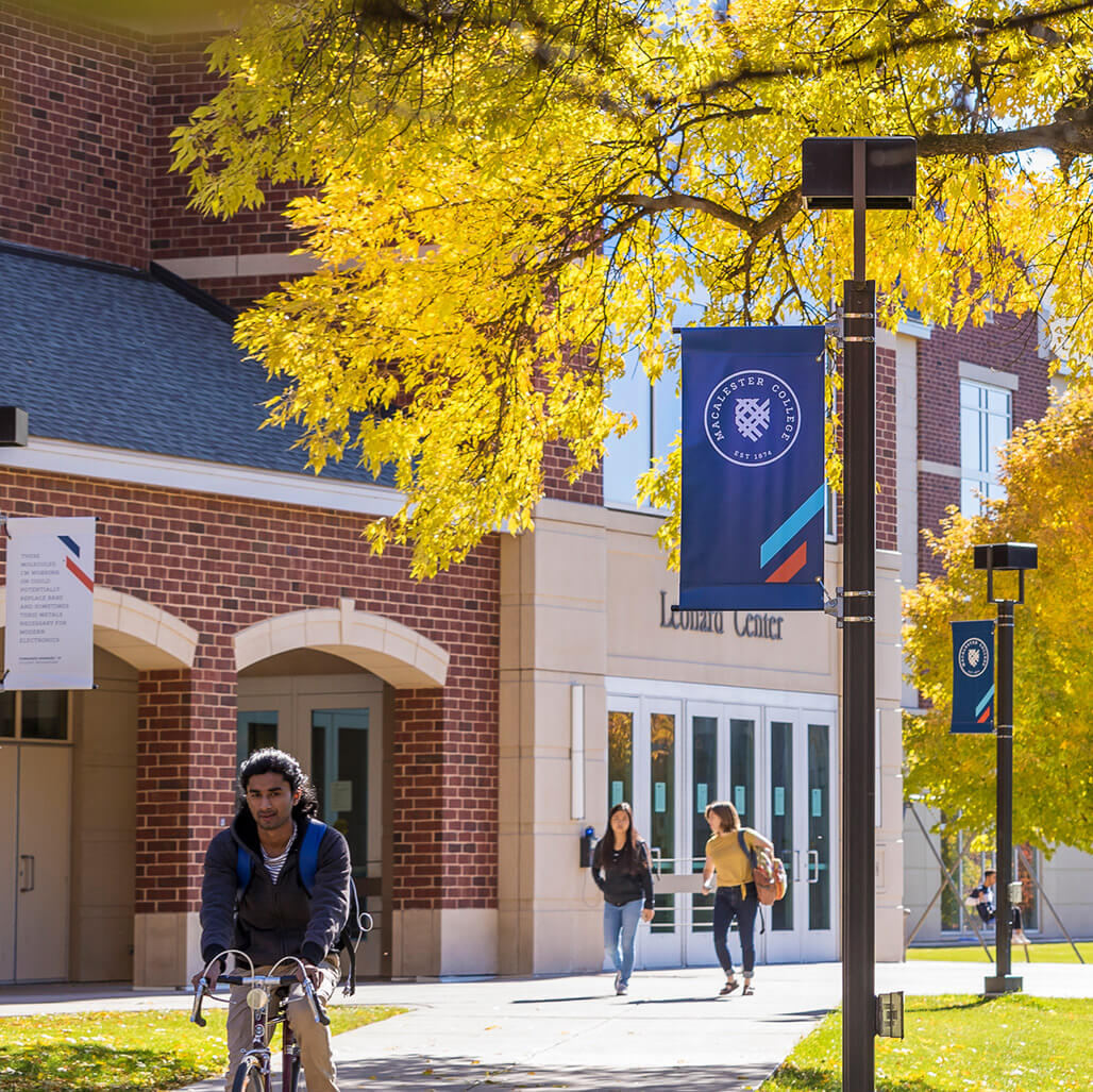 Students biking and walking in front of the Leonard Center