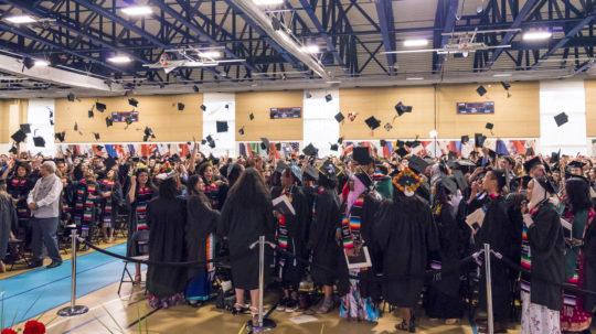 Photo of graduates throwing mortar boards at commencement ceremony