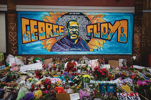 Photo of a mural of George Floyd with flowers laid in front of it