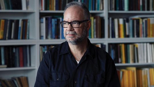 Photo of James Colliander sitting in front of a bookshelf