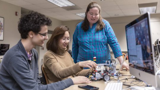 Photo of Susan Fox watching two students build a robot