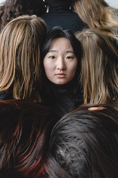 Photo of Long Nguyen looking at the camera surrounded by five other students with their backs turned to the camera