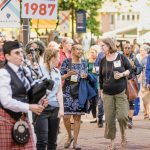Class of 1987 walks along campus with a bagpiper