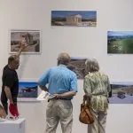 Professor showing art to two alumni