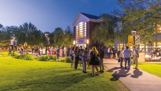 Group of alumni gathered on campus at night