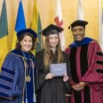 A graduating student poses with President Suzanne Rivera and Provost Lisa Anderson-Levy at Macalester's 2022 December Graduation.