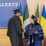 President Suzanne Rivera shakes hands with a graduate as she presents them with their diploma.