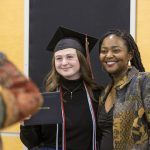 A graduating student poses next to another person as a photo is taken at Macalester's 2022 December Graduation.