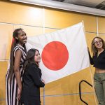 Three students hold the Japanese flag